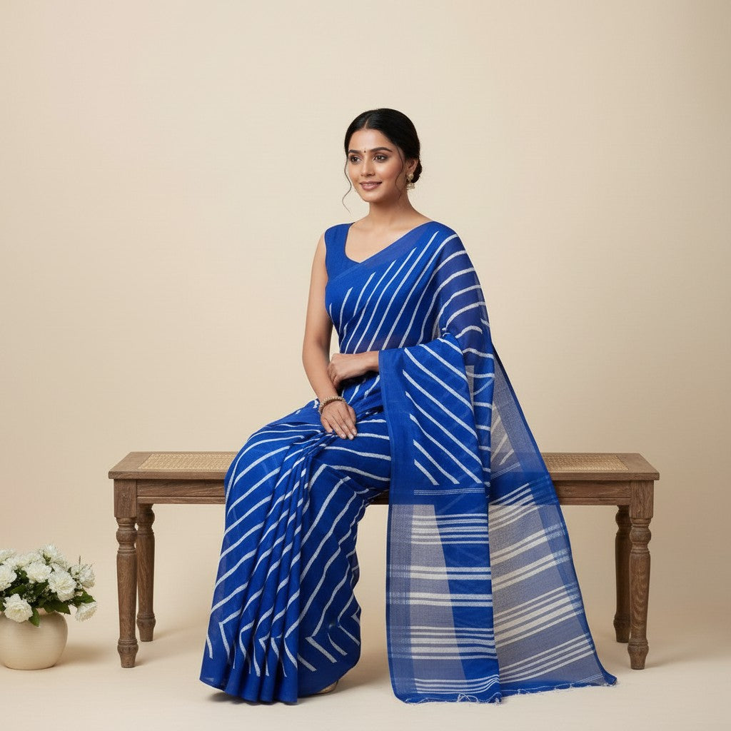 Shafusion blue georgette saree with white diagonal stripes worn by a woman sitting on a wooden bench