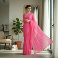 Shafusion pink georgette plain saree worn by a woman standing in a bright living room with a flowing drape