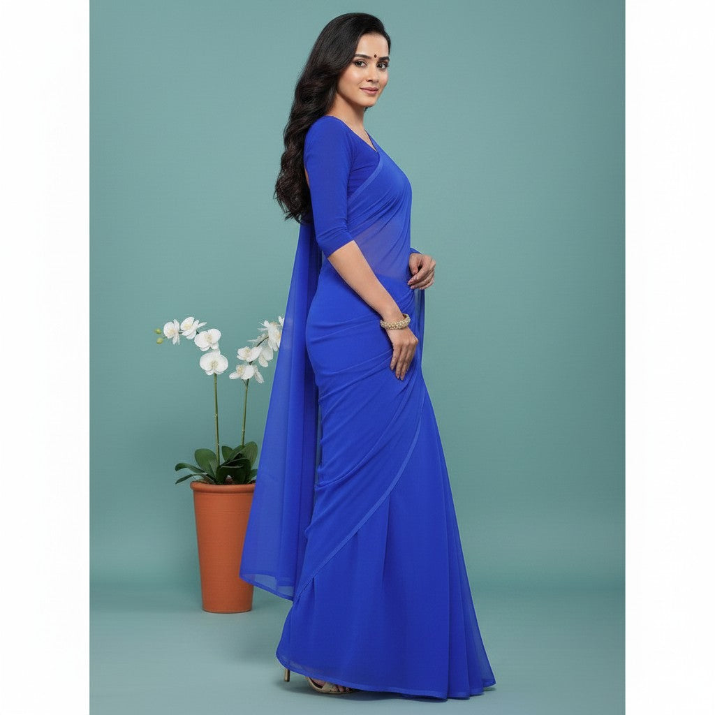 Shafusion royal blue georgette plain saree with matching blouse worn by a woman standing next to a potted orchid